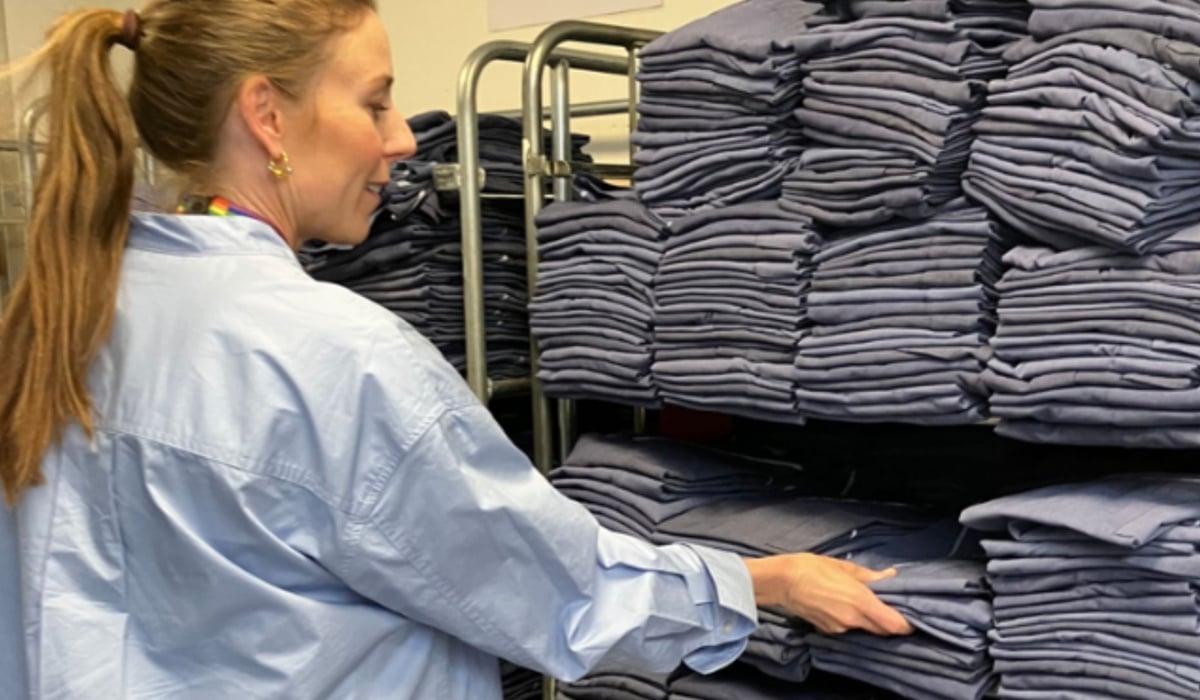 Bild på en kvinna framför en stor mängd sjukhuskläder