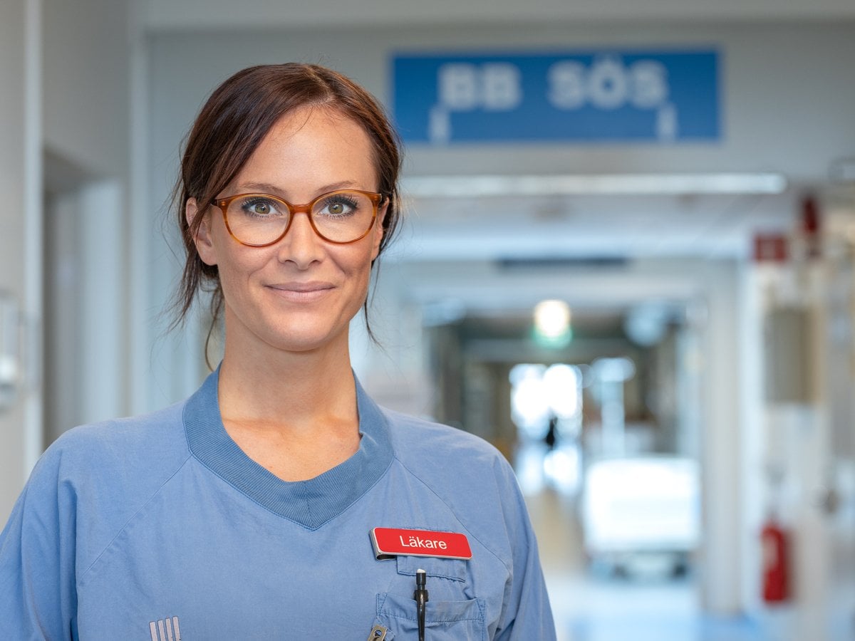 kvinnlig läkare i korridor BB Sös skylt i taket