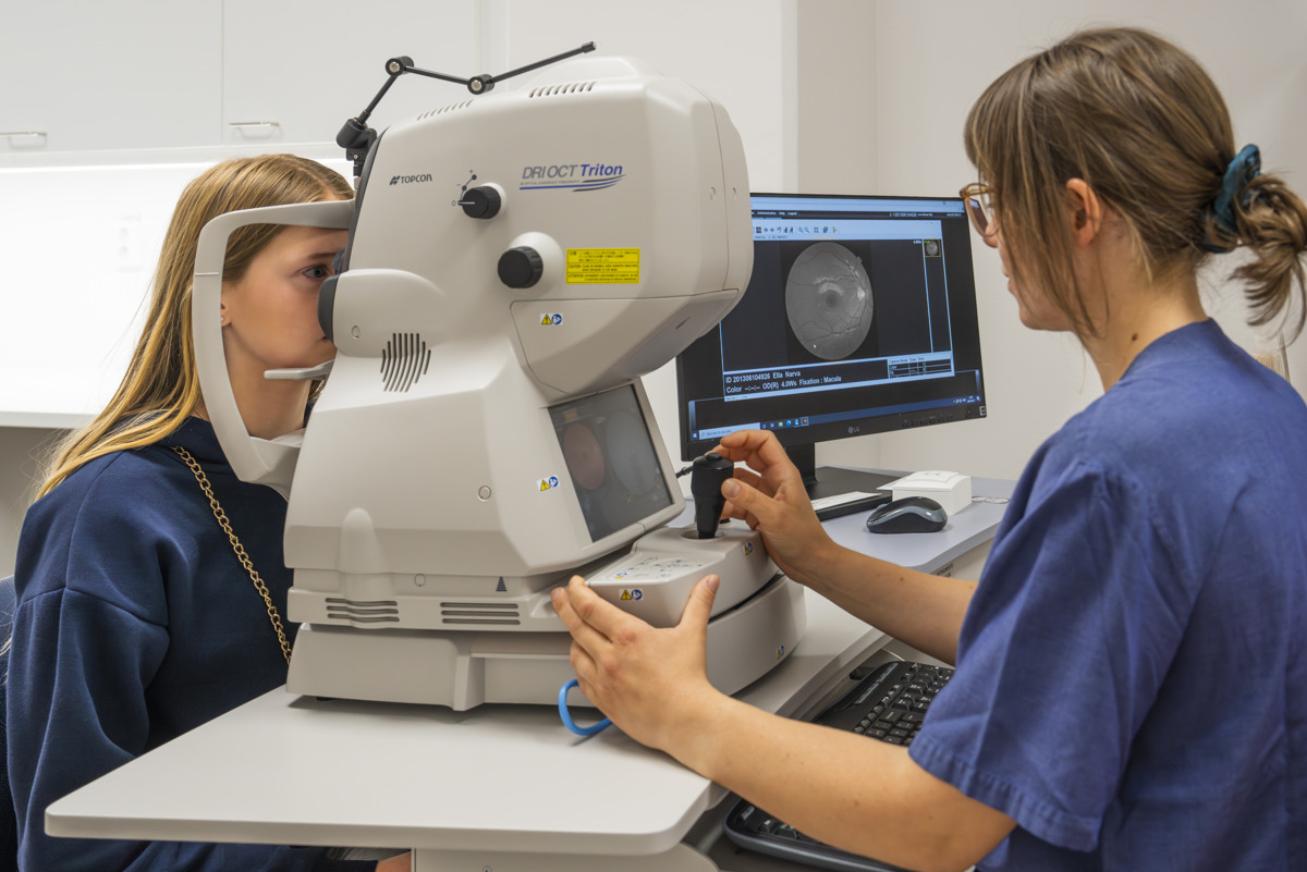 En sjuksk&ouml;terska g&ouml;r en &ouml;gonunders&ouml;kning p&aring; en ung kvinna som tittar in i en unders&ouml;kningsmaskin.