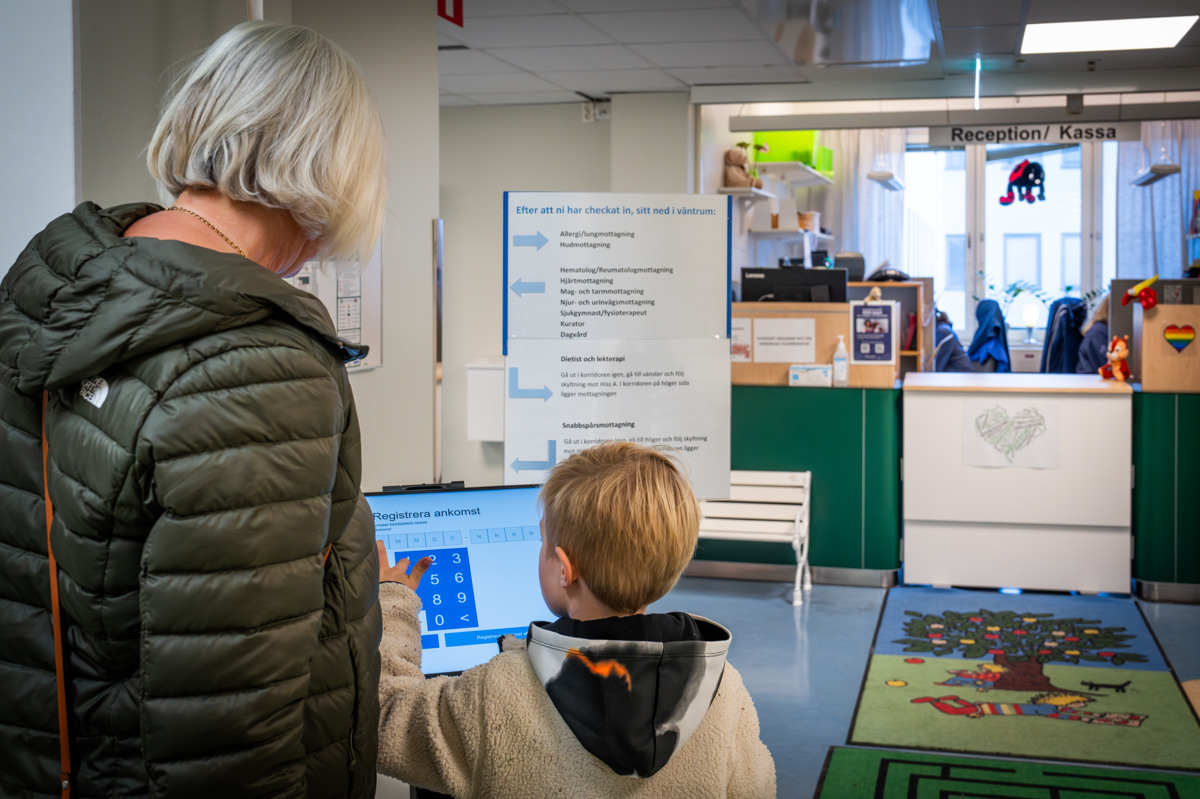 En kvinna och ett barn tittar p&aring; en datorsk&auml;rm i en reception
