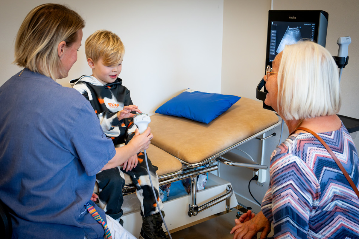 En kvinna i sjukhuskl&auml;der visar en pojke ett munstycke p&aring; en ultraljudsmaskin