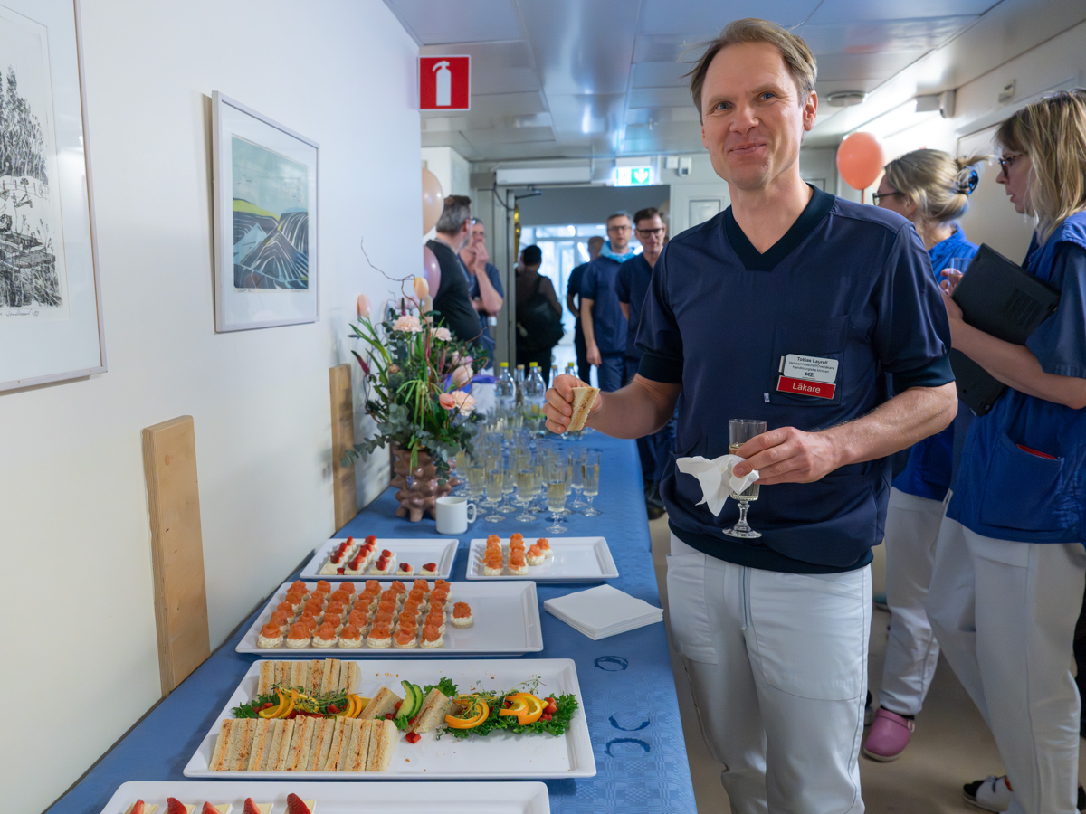 Läkare fotograferad vid en bord med snittar hållandes i ett glas