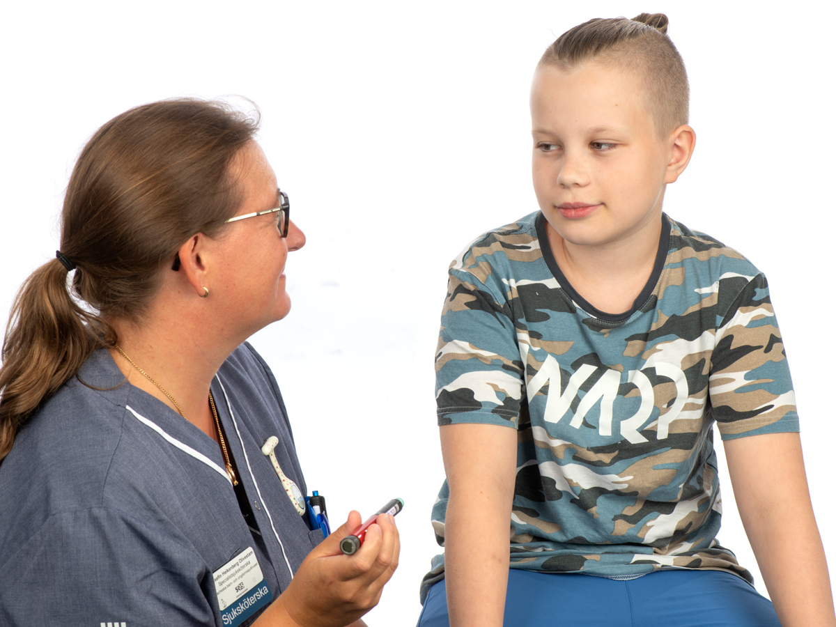 Kvinna i sjukhuskläder som håller i en insulinspruta sitter bredvid en ung pojke