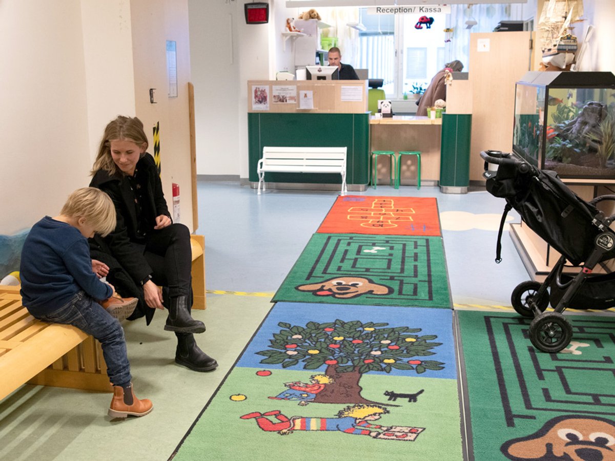 Bild på kvinna och ung pojke som sitter på en bänk i ett väntrum