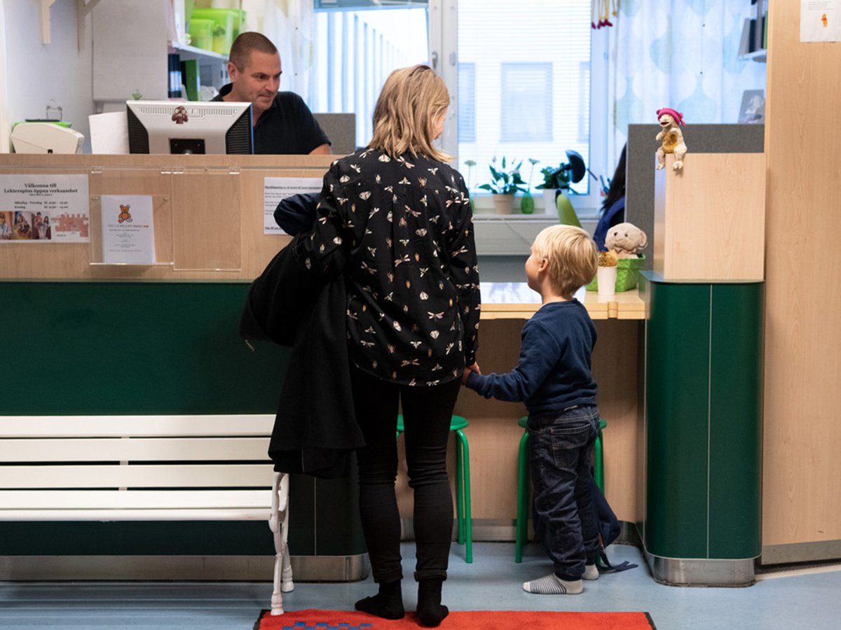 Kvinna och ung pojke som står vid en reception och pratar med en man