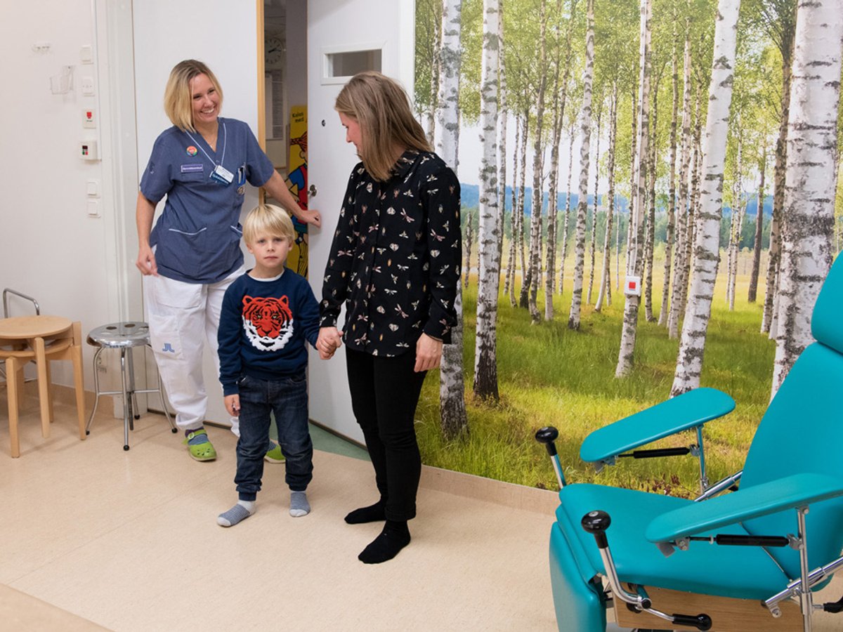 En kvinna i sjukhuskläder som stänger en dörr och en annan kvinna som håller en ung pojke i handen