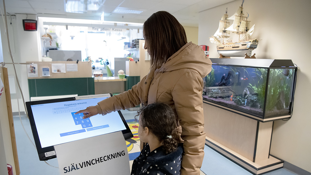 En kvinna och ett barn som står framför en stor skärm