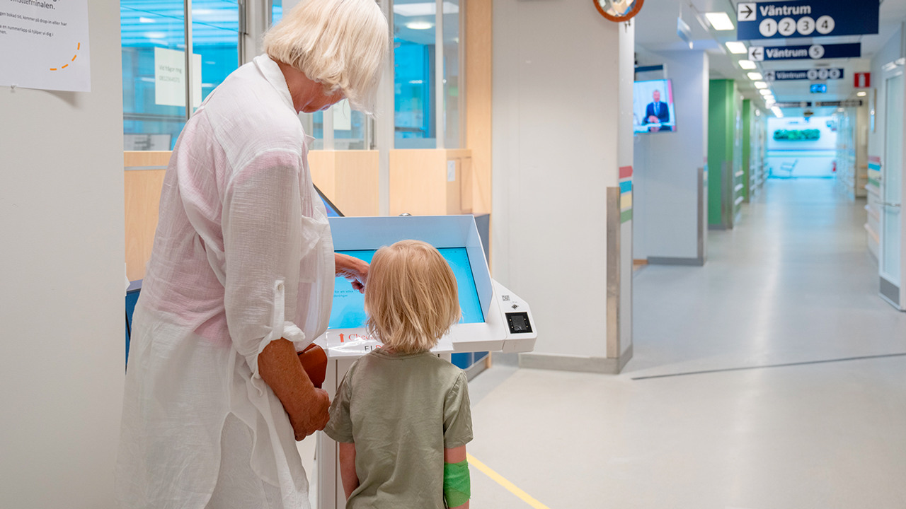 kvinna och barn vid sjukhusets självincheckning