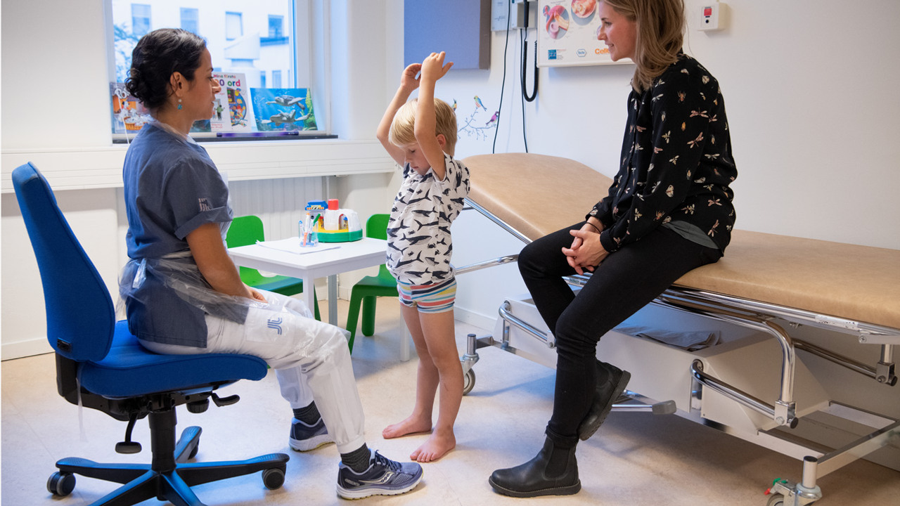 En barn st&aring;r mellan tv&aring; vuxna kvinnor med h&auml;nderna upp