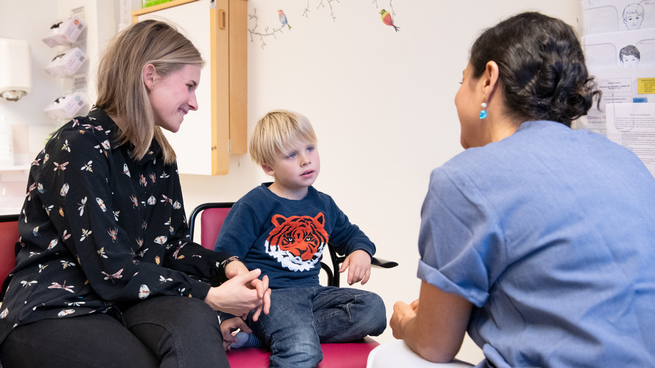 En ung pojke och tv&aring; vuxna sitter i ett rum och tittar p&aring; varandra