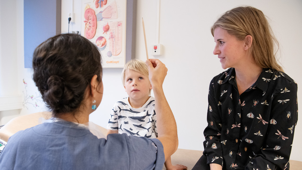 En kvinna h&aring;ller upp en penna framf&ouml;r en ung pojke