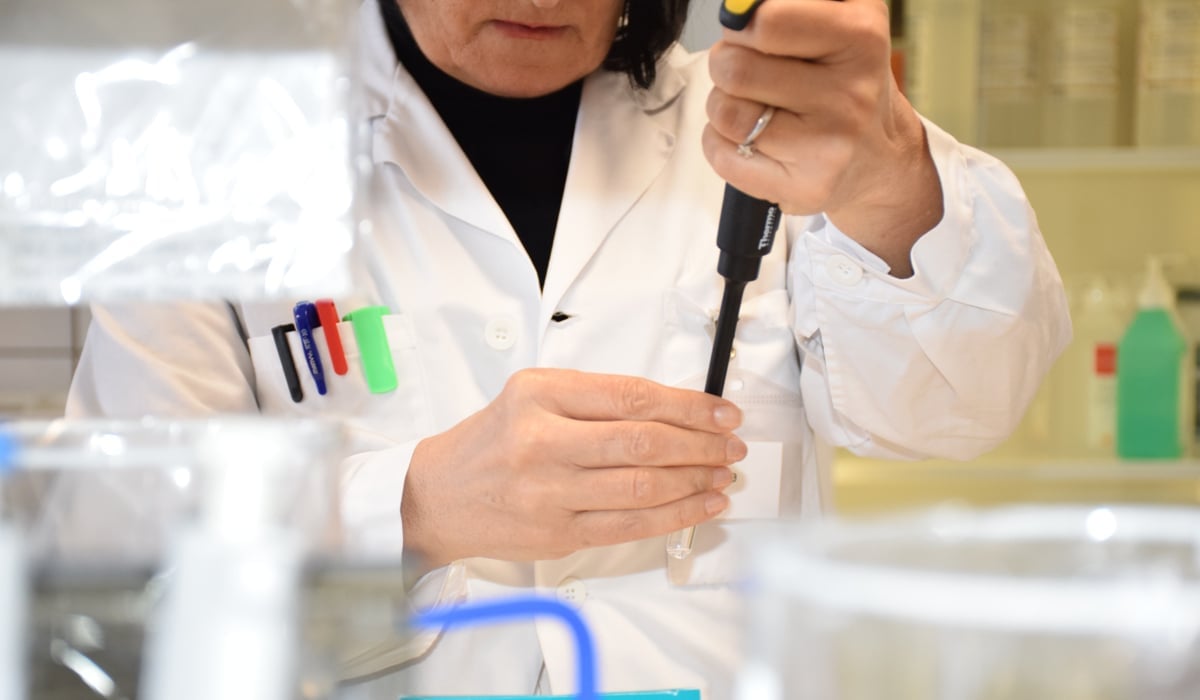 kvinnlig forskare i vit rock, ansikte syns ej i labbmiljö