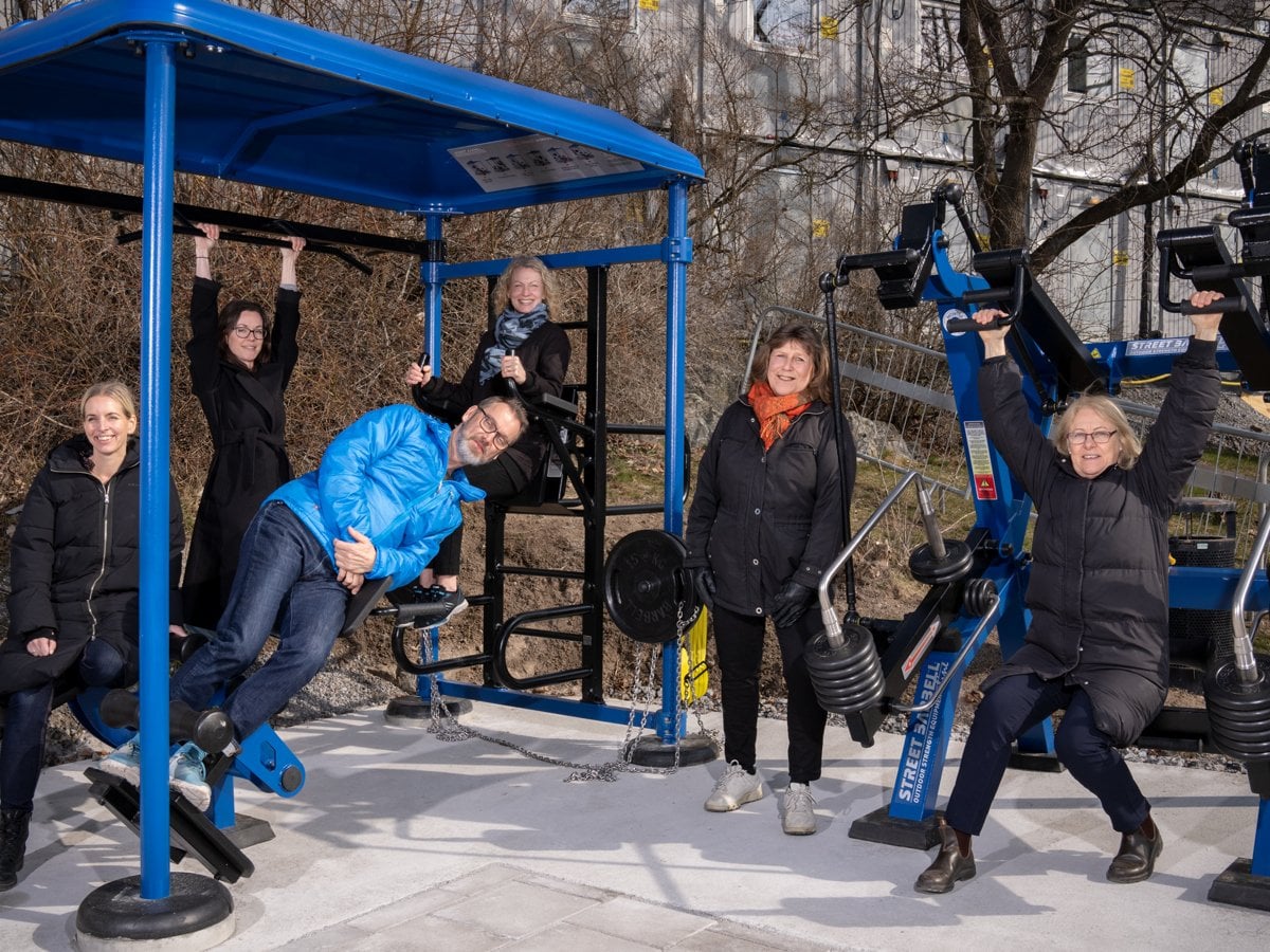 utegym i blått och svart sex kvinnor i svarta jackor en man i blå jacka liggande i luften.