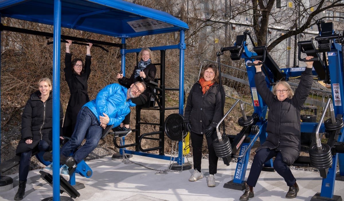 utegym i blått och svart sex kvinnor i svarta jackor en man i blå jacka liggande i luften.