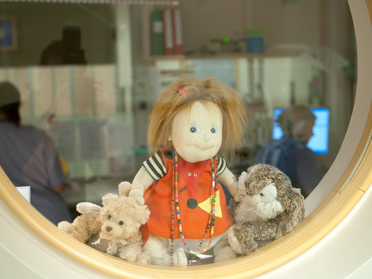 docka och gosedjur i runt fönster, personal i bakgrund vid datorer