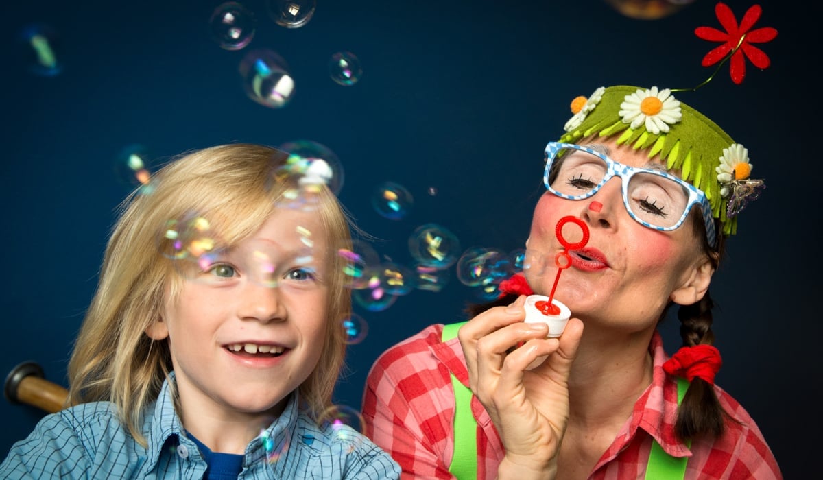 Bild på en ung pojke och en kvinna utklädd till clown