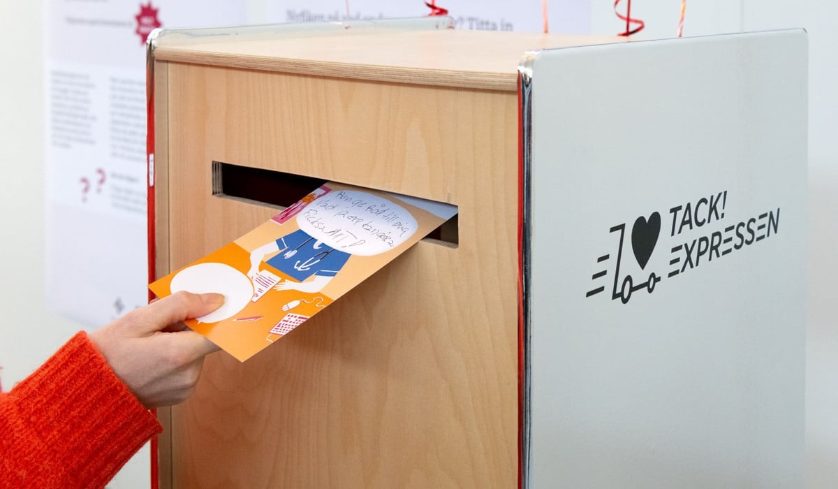 En person som lägger ett vykort i en brevlåda.