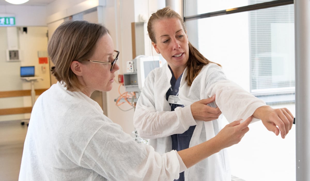 En kvinna som håller i ärmen på en annan kvinnas sjukhusrock