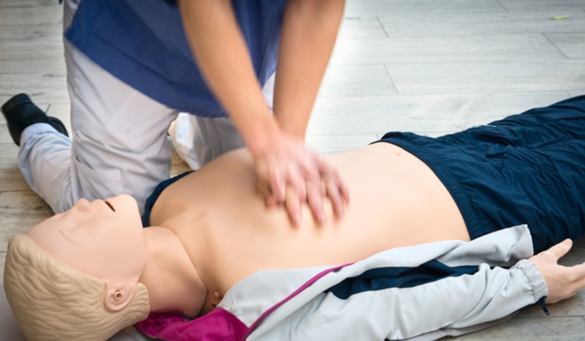 händer som trycker på docka övar hjärt- och lungräddning.