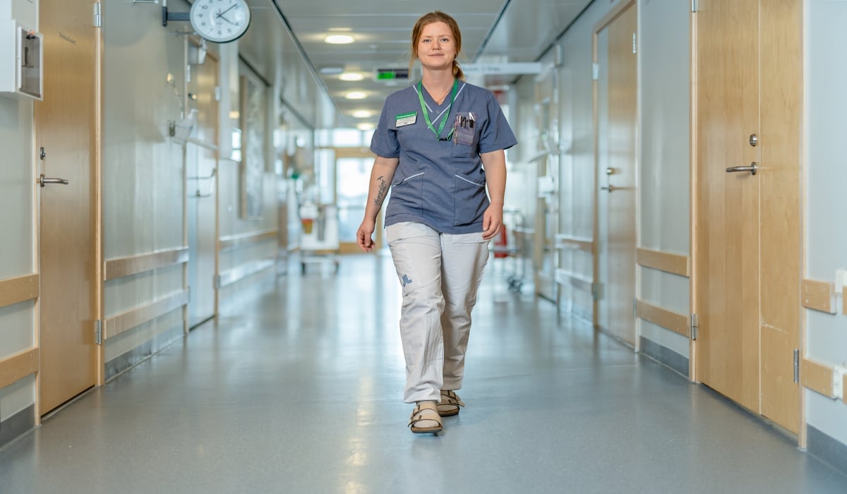 kvinnlig undersköterska går genom sjukhuskorridor