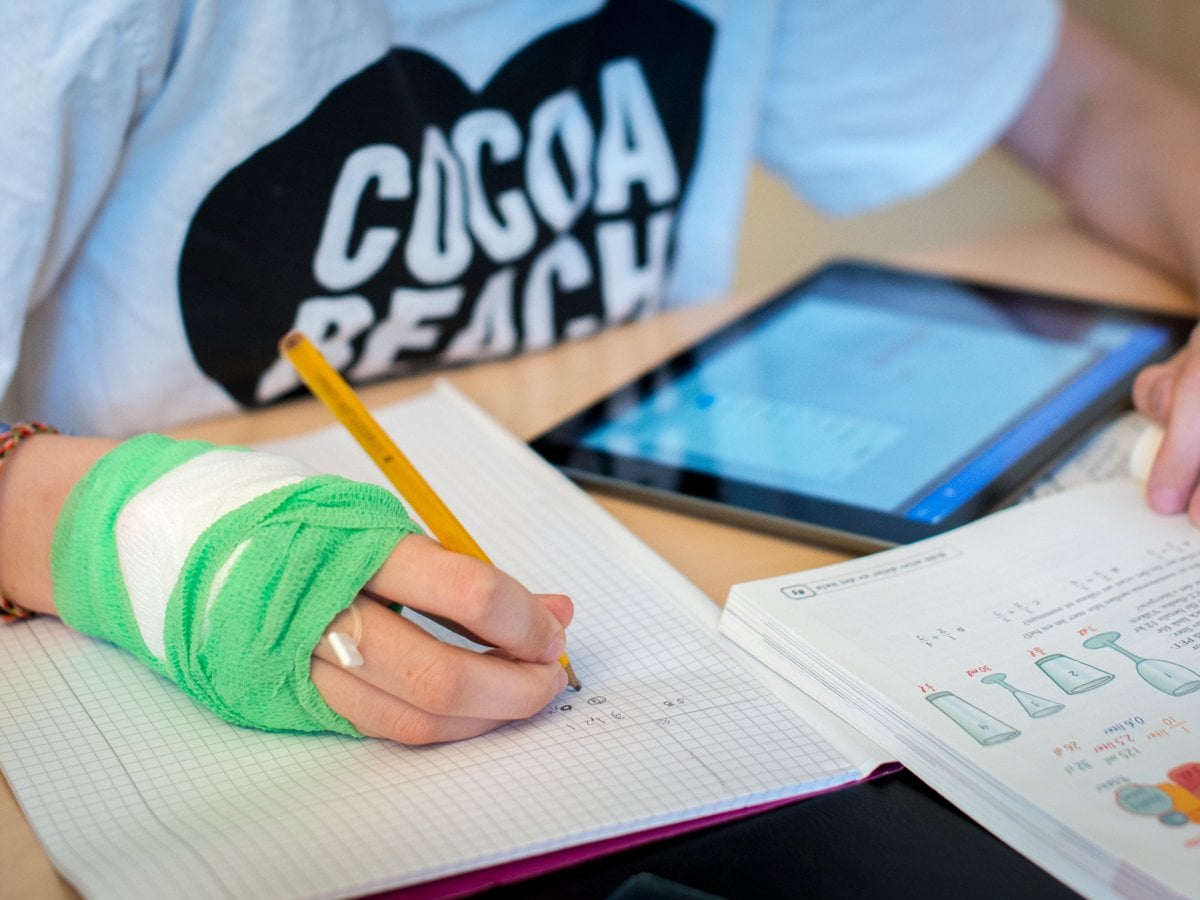 En person som gör sina läxor med bandage på sin hand