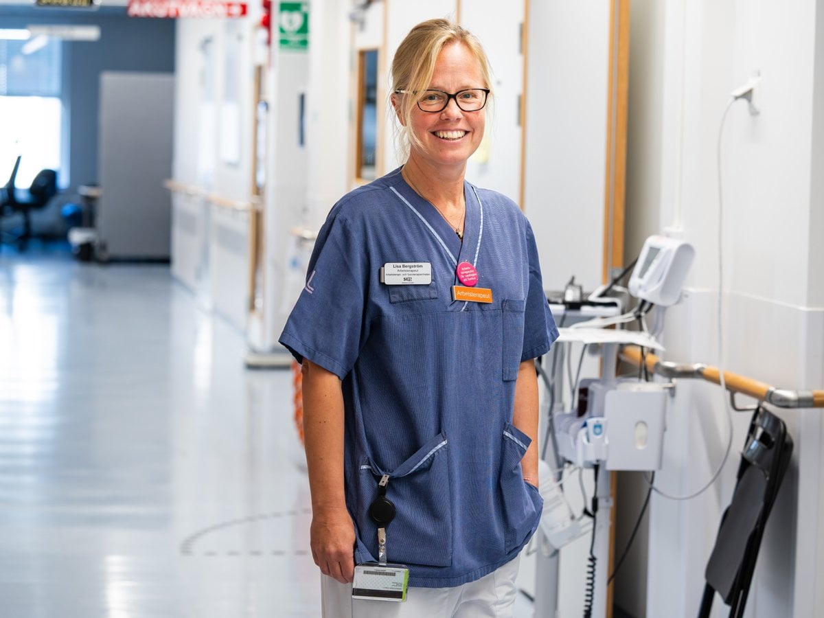 Kvinnlig arbetsterapeut i sjukhuskorridor.