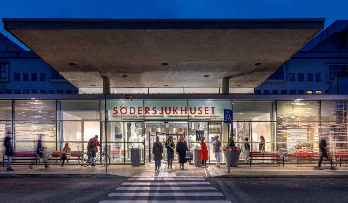 Bild på Södersjukhusets huvudentré men ett antal människor som står på utsidan