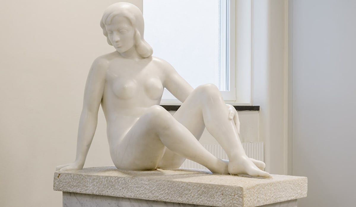 staty i marmor av naken kvinna på marmorstod