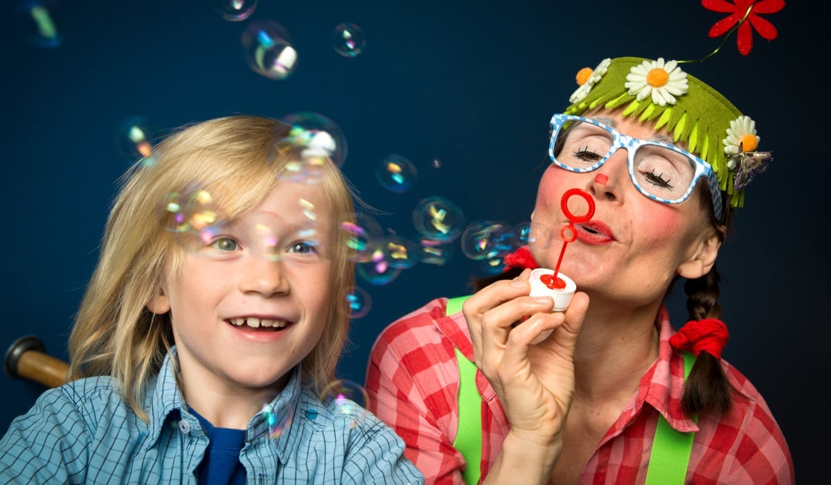 Bild på en ung pojke och en kvinna utklädd till clown