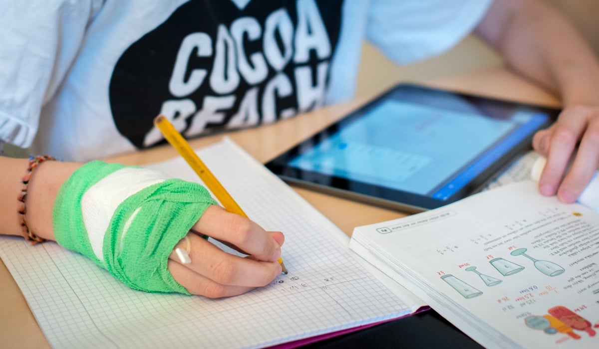 En person som gör sina läxor med bandage på sin hand