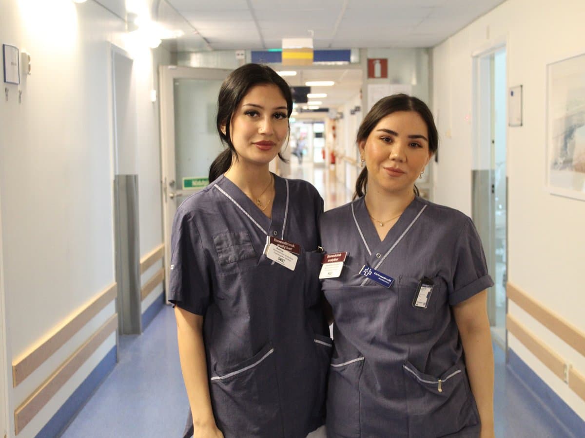 två kvinnor i vårdkläder tillsammans i sjukhuskorridor