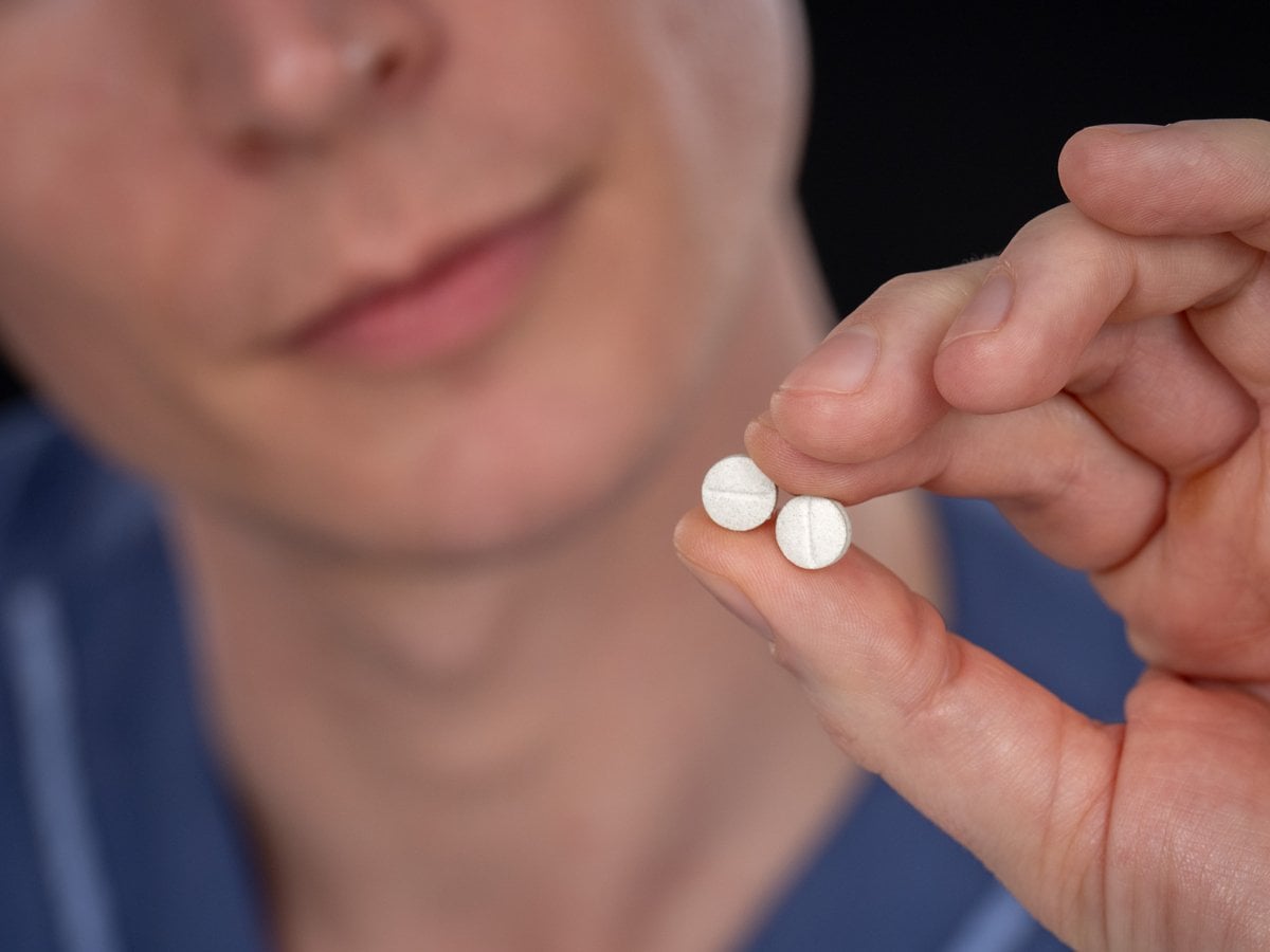 Närbild på en person som håller i två stycken tabletter