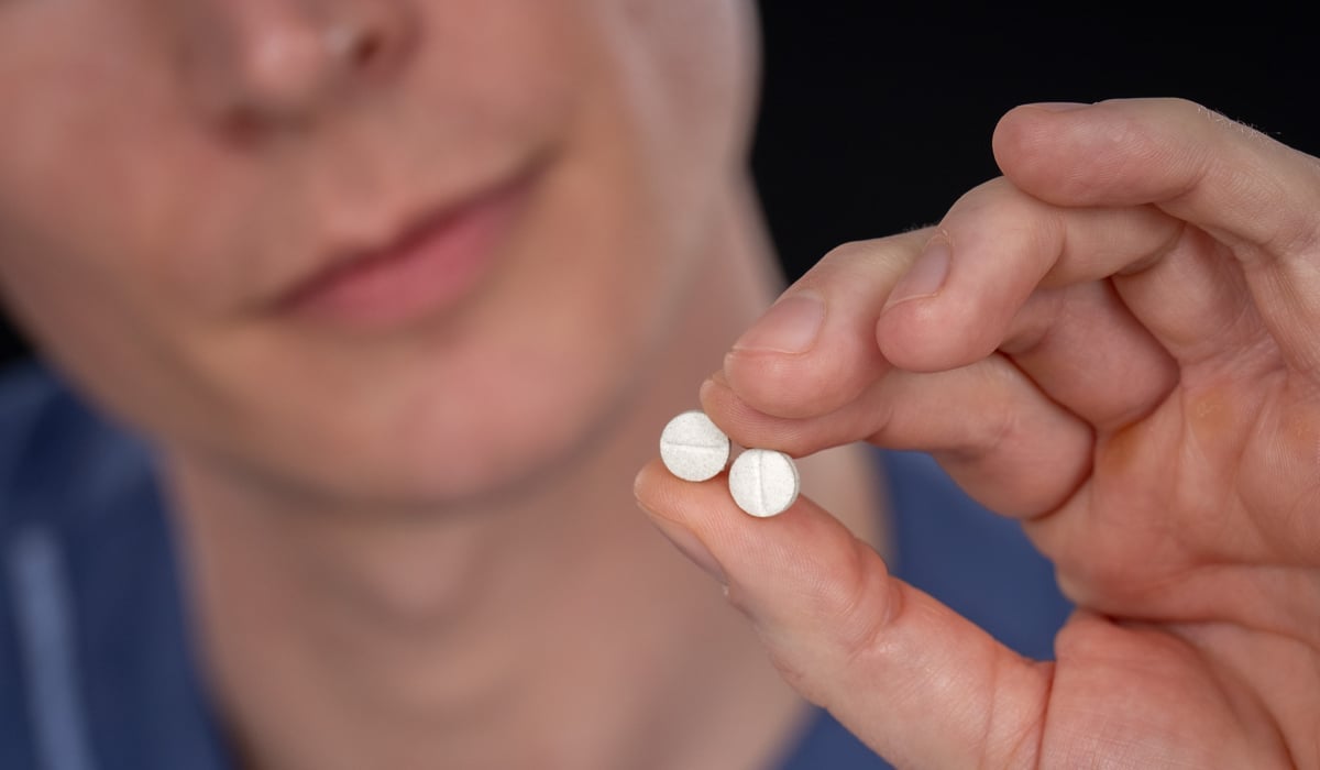 Närbild på en person som håller i två stycken tabletter