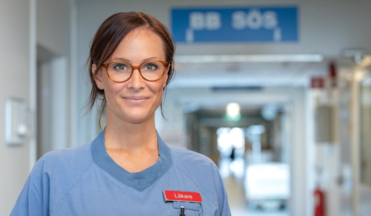 kvinnlig läkare i korridor BB Sös skylt i taket