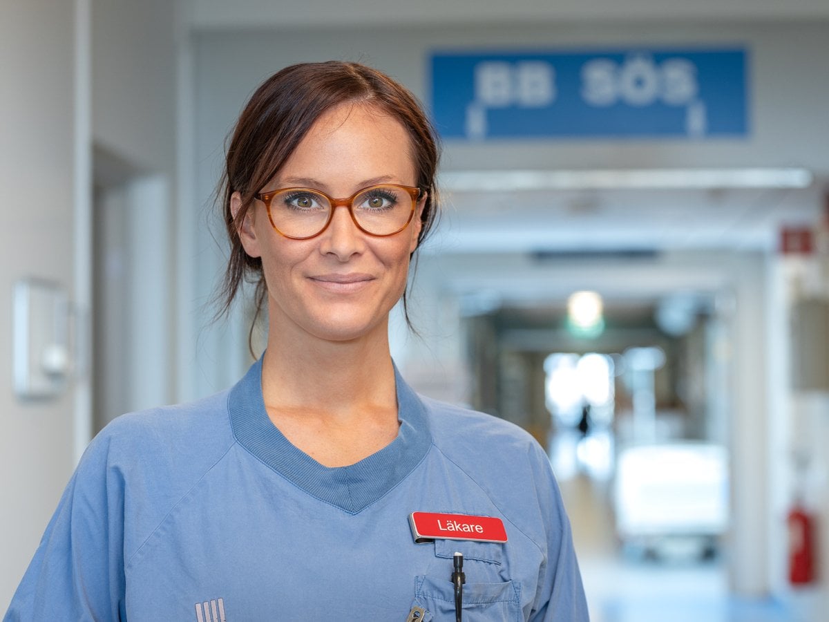 kvinnlig läkare i korridor BB Sös skylt i taket
