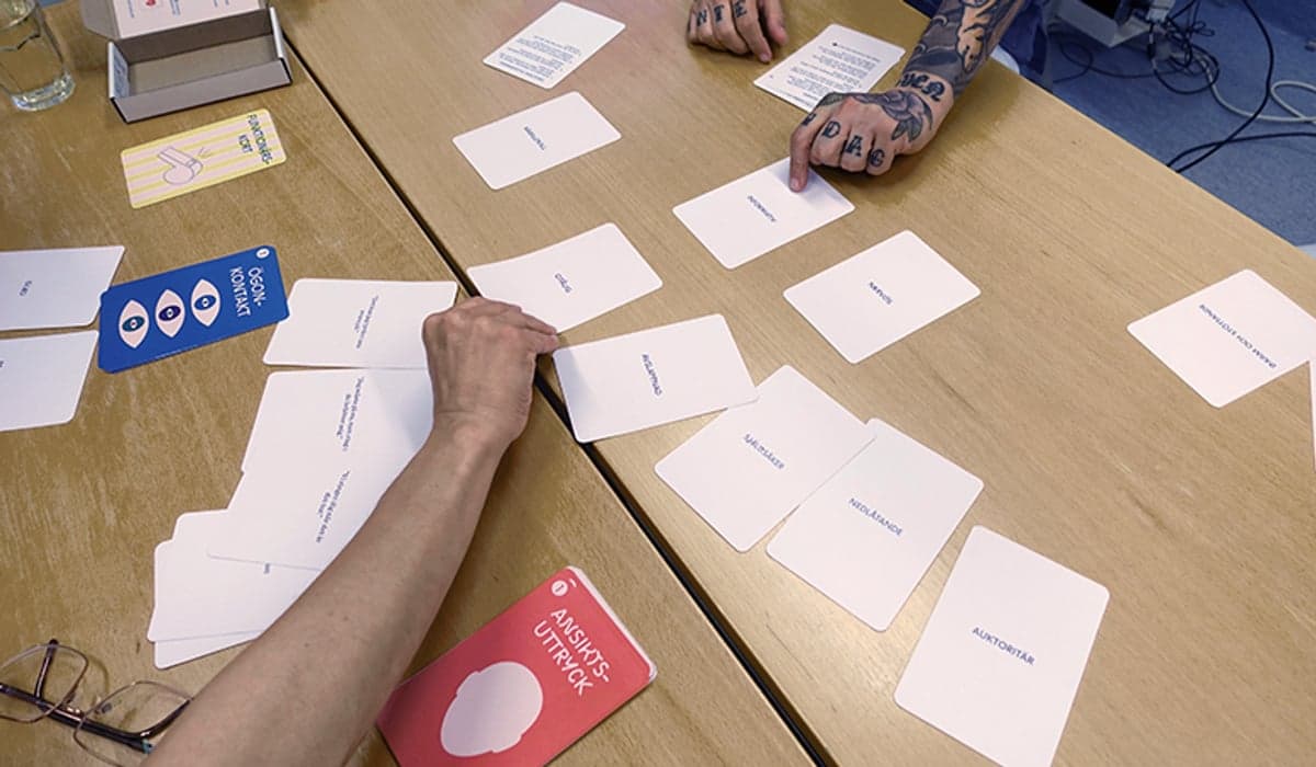 Bild på ett bord där två eller flera personer spelar ett spel med spelkort