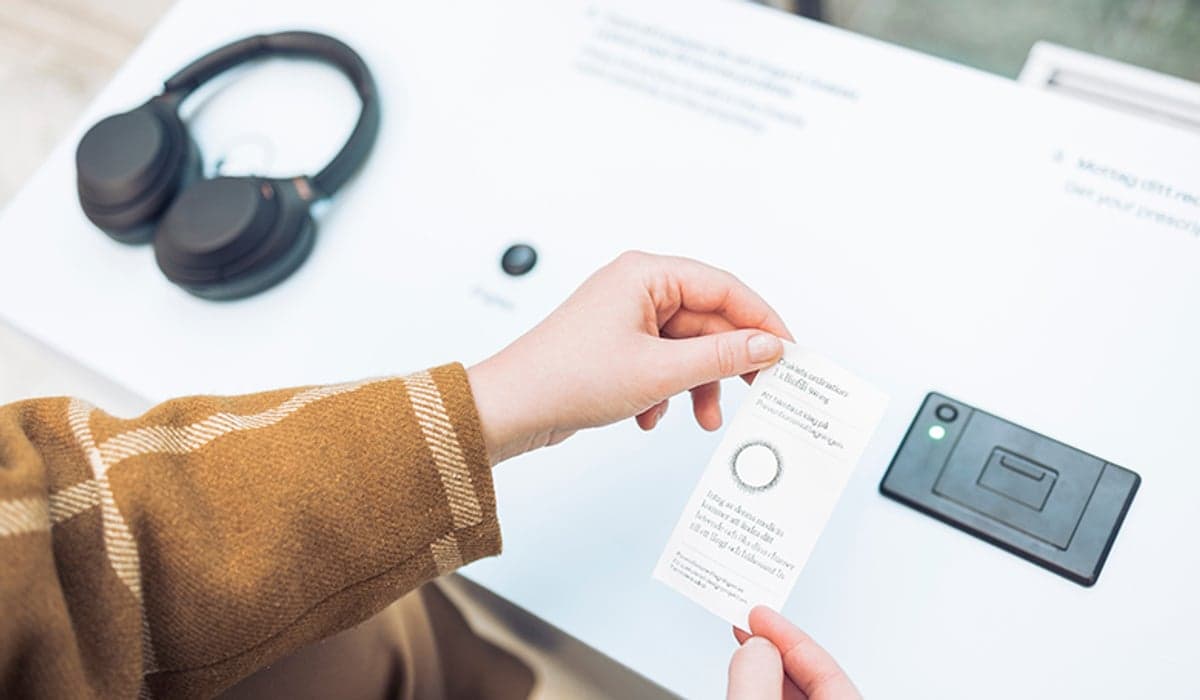 Bild på två händer som håller i ett kort vid en monter