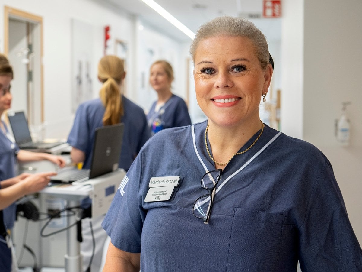 Bild på en kvinna som är vårdenhetschef med 5 kvinnor i sjukhuskläder i bakgrunden