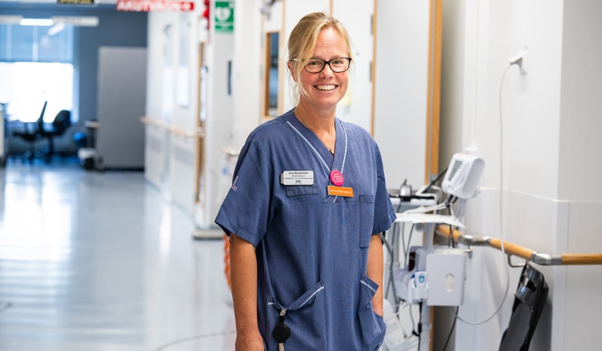 Kvinnlig arbetsterapeut i sjukhuskorridor.