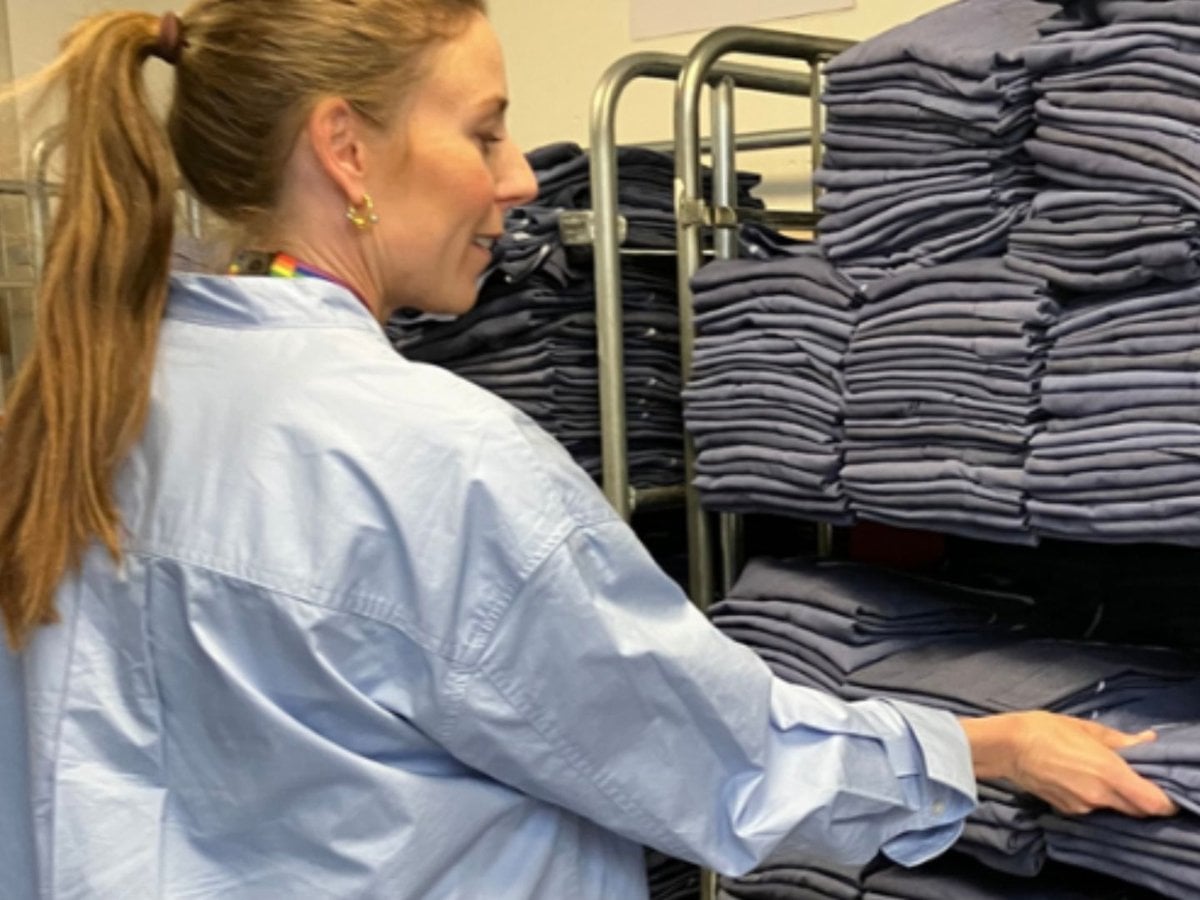 Bild på en kvinna framför en stor mängd sjukhuskläder