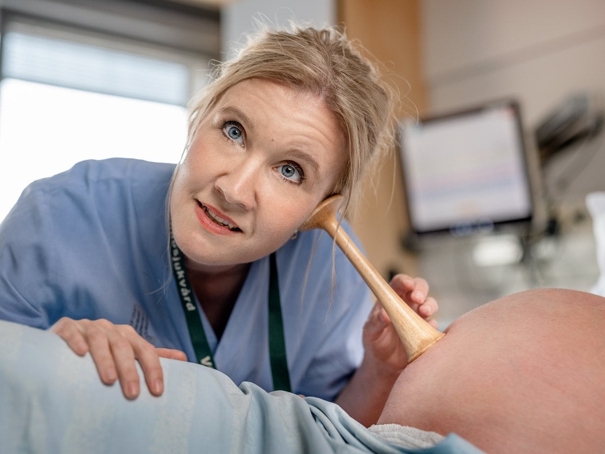 Barnmorska lyssnar med tratt på gravid mage.