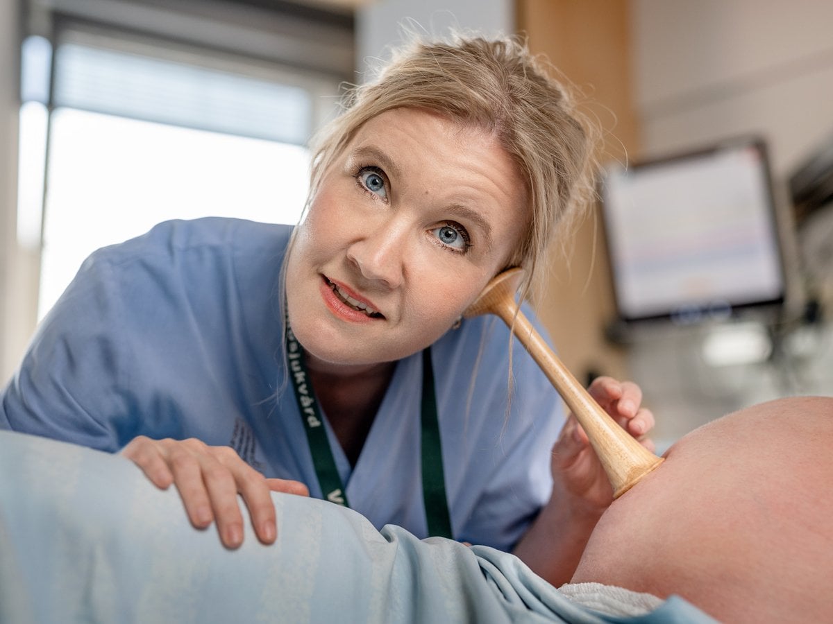Barnmorska lyssnar med tratt på gravid mage.