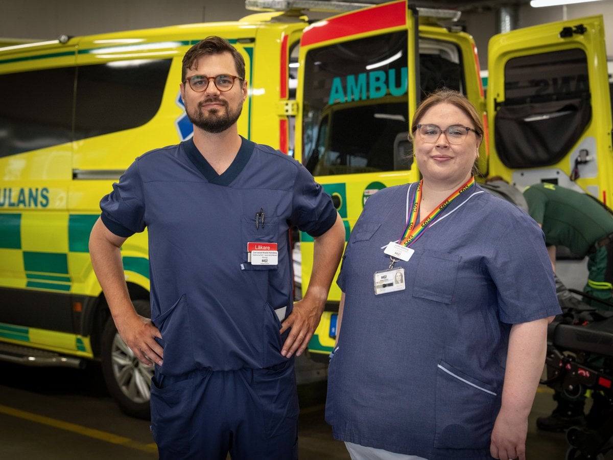 Man och kvinna i sjukhuskläder framför ambulans inomhus