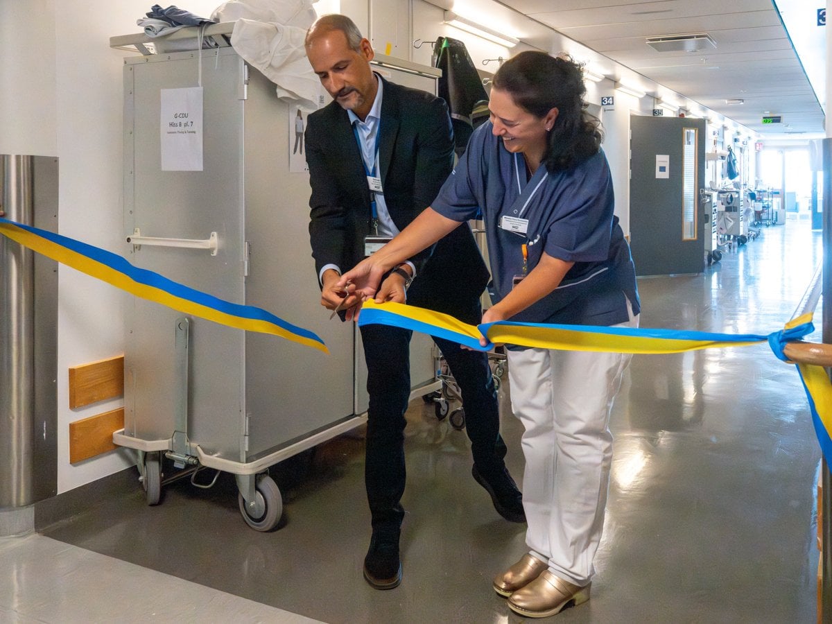 Bild på en man i kostym och en kvinna i sjukhuskläder som klipper ett invigningsband