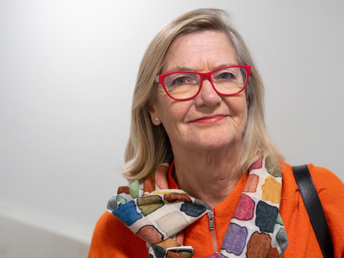 porträtt Lotti Helström röda glasögon, rutig sjal, orange kavaj