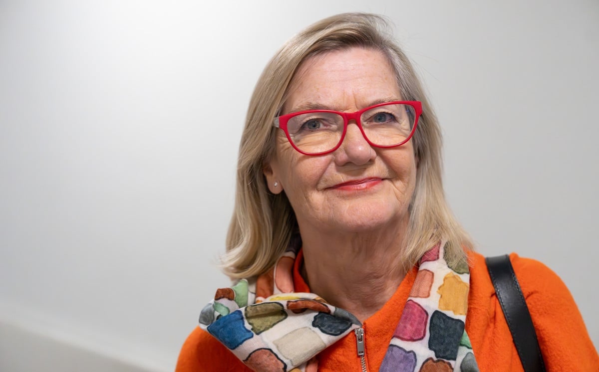 porträtt Lotti Helström röda glasögon, rutig sjal, orange kavaj