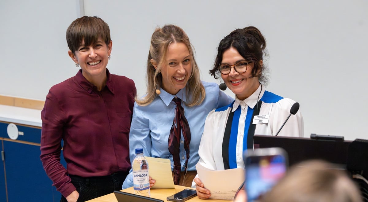 tre skrattande kvinnor vid talarbänk