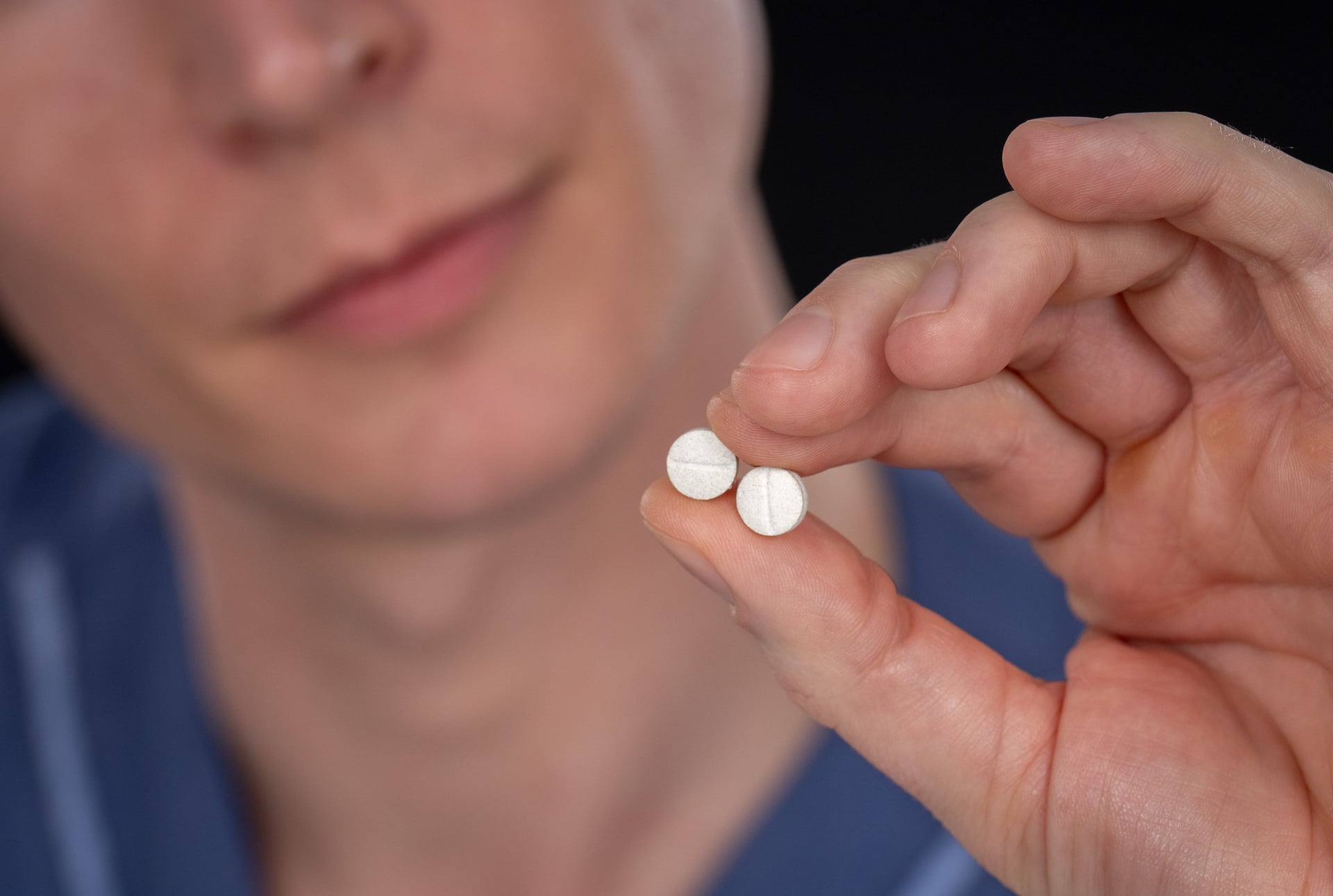 Närbild på en person som håller i två stycken tabletter