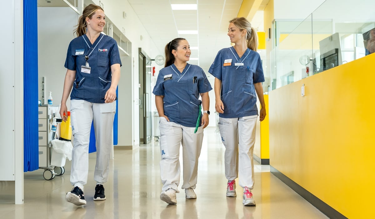 tre kvinnliga medarbetare i sjukhuskorridor