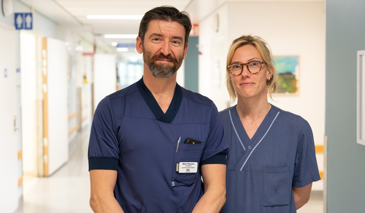 man och kvinna klädda i sjukhuskläder står i korridor